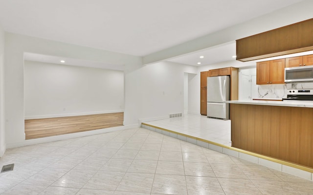 kitchen with appliances with stainless steel finishes, open floor plan, light countertops, recessed lighting, and light tile patterned floors