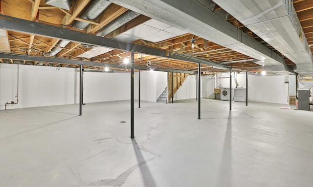 below grade area featuring independent washer and dryer, stairway, and heating unit