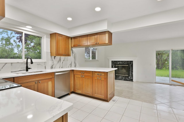 kitchen featuring stainless steel dishwasher, a sink, light countertops, a peninsula, and recessed lighting
