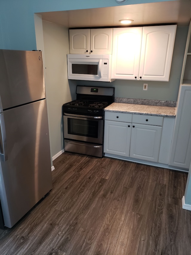 kitchen featuring white cabinetry, baseboards, stainless steel appliances, and dark wood-style floors