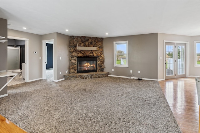 unfurnished living room with a wealth of natural light, baseboards, and a stone fireplace