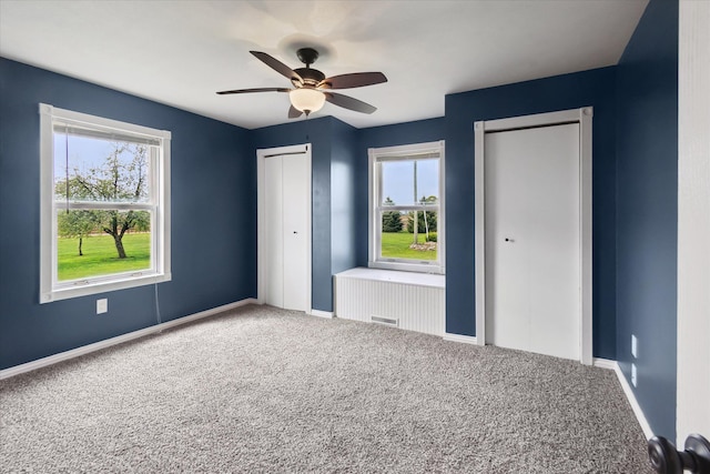 unfurnished bedroom with a ceiling fan, baseboards, visible vents, two closets, and carpet floors