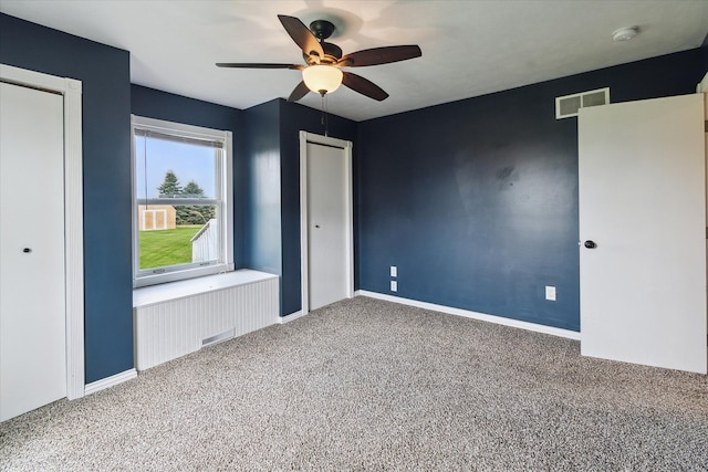 unfurnished bedroom featuring baseboards, carpet floors, a ceiling fan, and visible vents