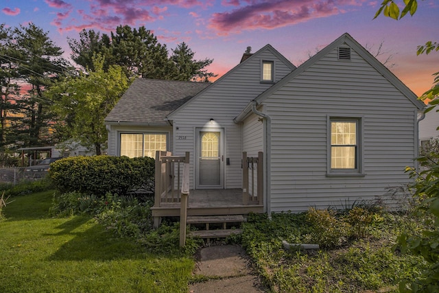 bungalow-style house with a front lawn, roof with shingles, a chimney, and a wooden deck