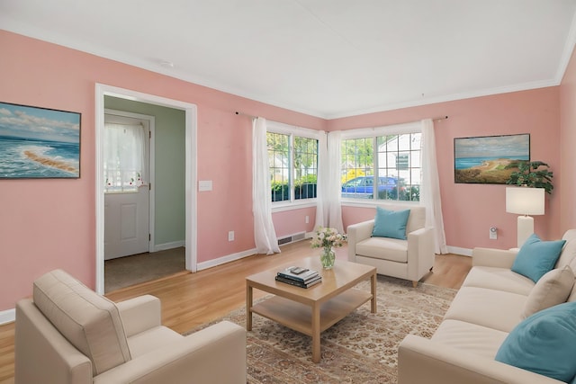 living room featuring ornamental molding, baseboards, visible vents, and light wood-style floors