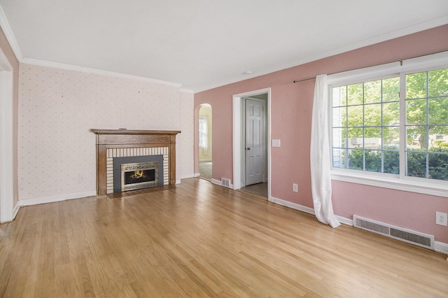 unfurnished living room featuring ornamental molding, arched walkways, light wood-type flooring, and visible vents