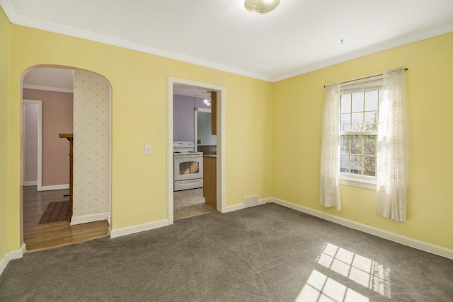 empty room featuring carpet floors, visible vents, baseboards, arched walkways, and ornamental molding
