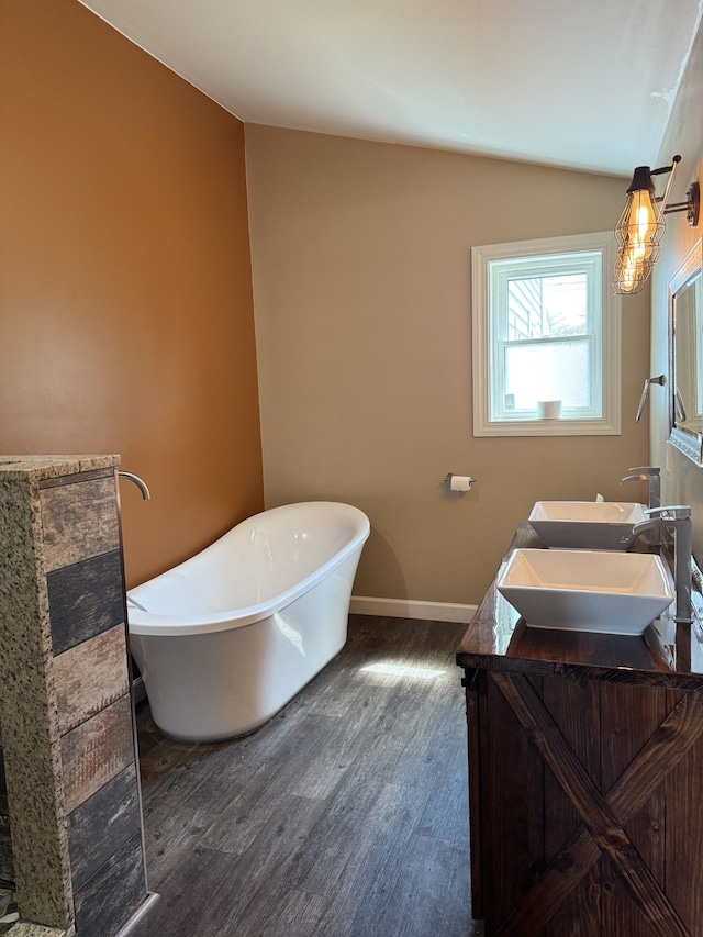 4212 4th St, Brown City, MI 48416 - bathroom featuring a sink, wood finished floors, vaulted ceiling, a soaking tub, and double vanity