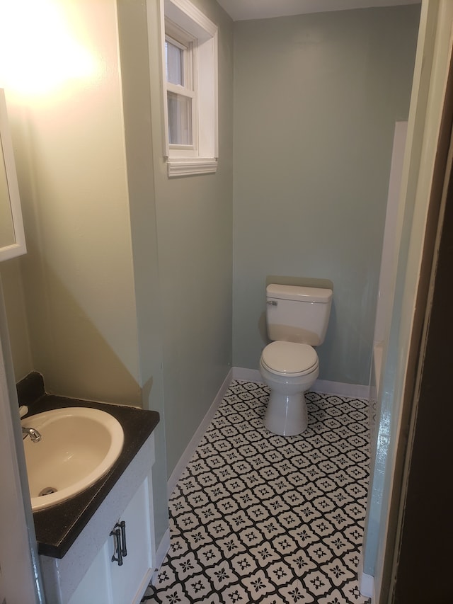 bathroom with toilet, baseboards, vanity, and tile patterned flooring