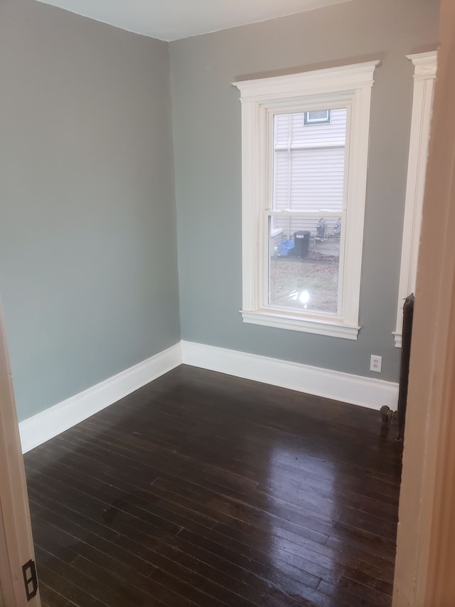 spare room with baseboards and dark wood-style floors