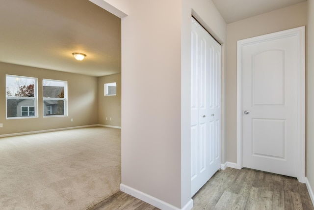 hall featuring light wood-style floors and baseboards