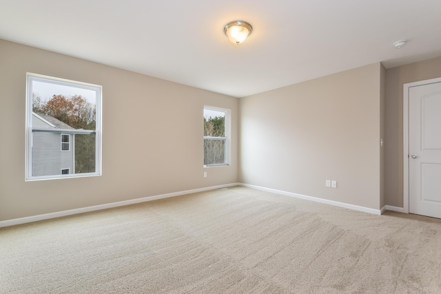 carpeted spare room with plenty of natural light and baseboards
