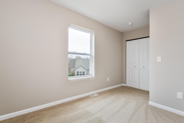 unfurnished bedroom with carpet flooring, a closet, visible vents, and baseboards