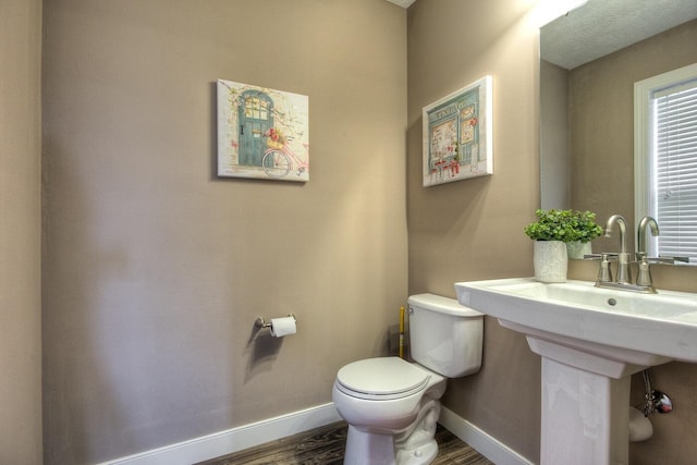 bathroom featuring toilet, baseboards, and wood finished floors