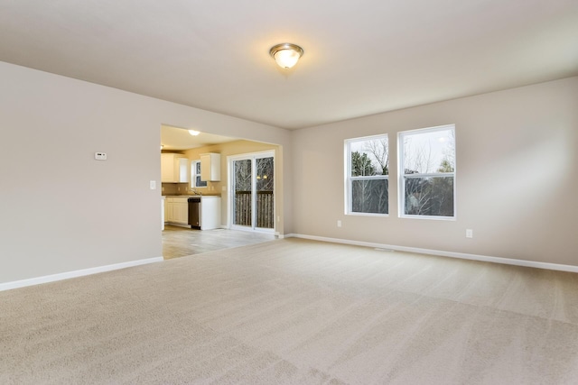 empty room featuring light carpet and baseboards