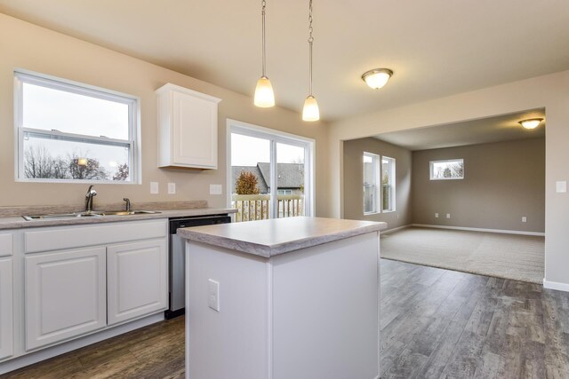 kitchen featuring a center island, decorative light fixtures, dishwasher, a sink, and open floor plan