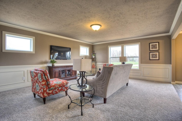 living room with wainscoting, crown molding, a textured ceiling, and carpet