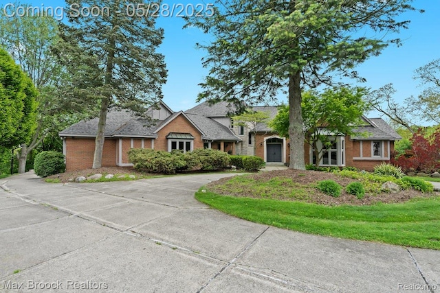 4395 Hickory Ct, Orchard Lake, MI 48323 - view of front facade with brick siding, curved driveway, and roof with shingles