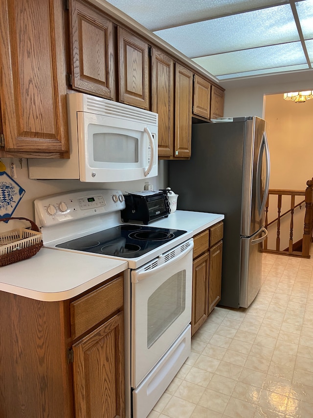 kitchen featuring white appliances, light flooring, brown cabinetry, and light countertops