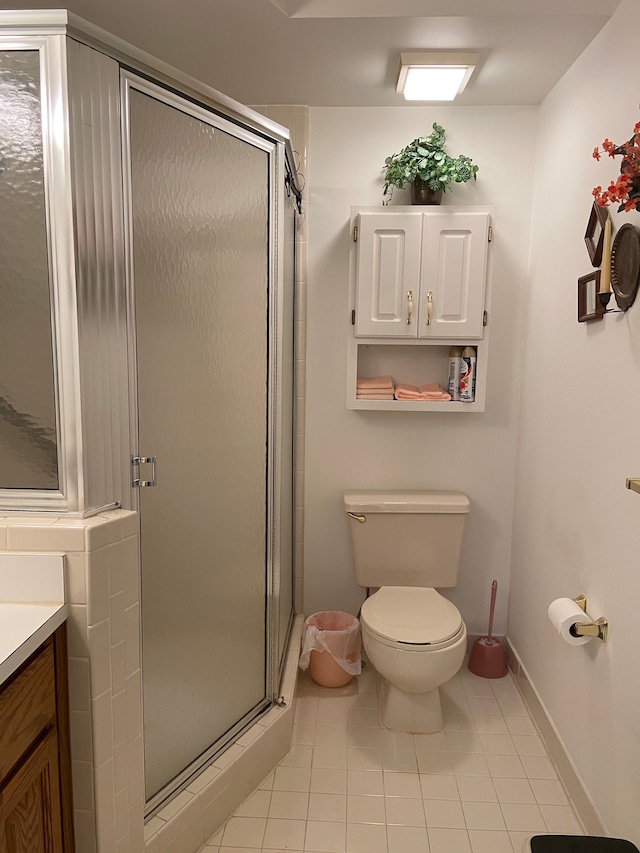 bathroom featuring tile patterned flooring, a shower stall, vanity, and toilet