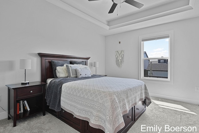 bedroom with a tray ceiling, light carpet, and a ceiling fan