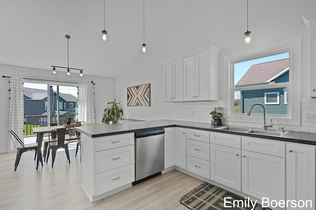 kitchen featuring white cabinetry, dark countertops, a sink, and dishwasher