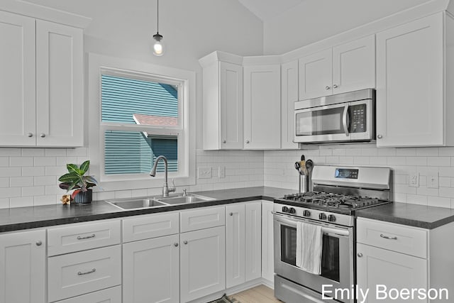 kitchen featuring a sink, white cabinetry, decorative backsplash, dark countertops, and appliances with stainless steel finishes