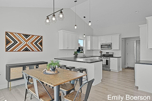 kitchen featuring a peninsula, dark countertops, appliances with stainless steel finishes, and white cabinetry