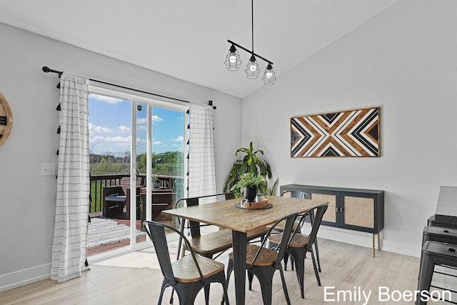 dining area featuring vaulted ceiling, light wood-style flooring, and baseboards