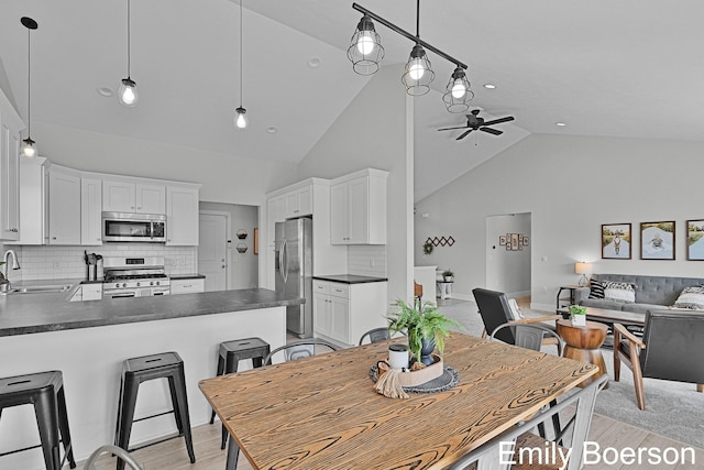 dining space with high vaulted ceiling, light wood-style flooring, and a ceiling fan