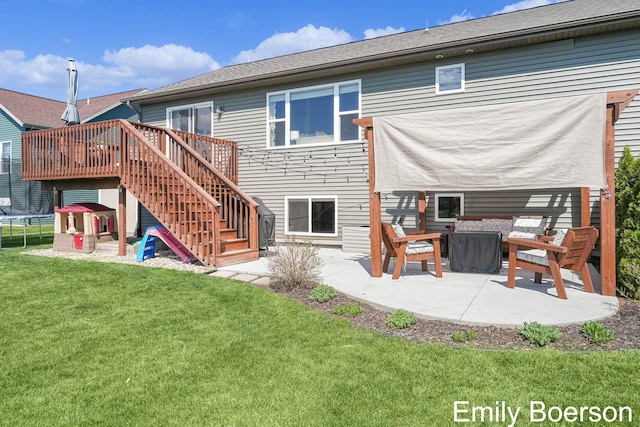 back of property featuring a trampoline, a patio, stairway, a wooden deck, and a lawn