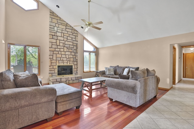 53201 Maranatha Ln, Wixom, MI 48393 - living room with high vaulted ceiling, ceiling fan, wood finished floors, a stone fireplace, and baseboards