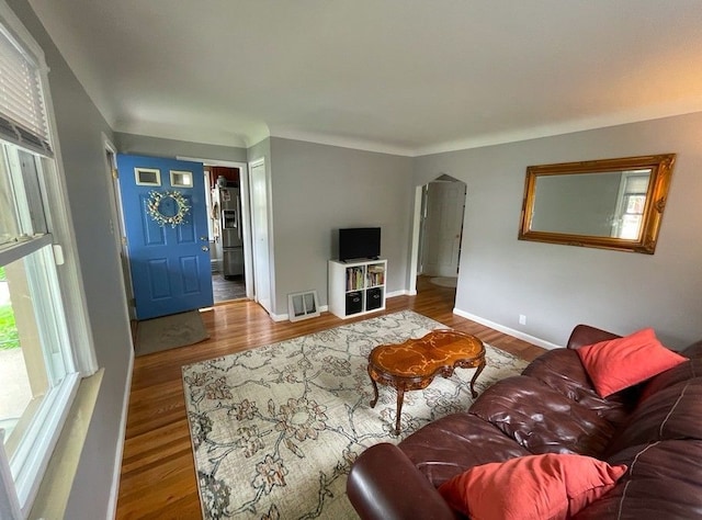 living room with visible vents, wood finished floors, baseboards, and arched walkways