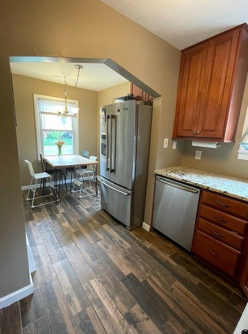 kitchen featuring dark wood-style flooring, stainless steel appliances, a wealth of natural light, and a notable chandelier