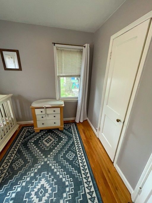 bedroom featuring baseboards, a nursery area, and light wood finished floors