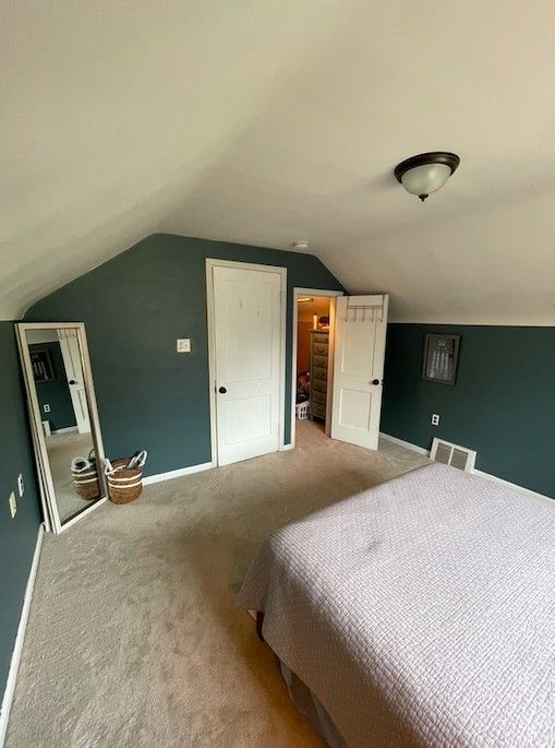 bedroom featuring carpet, visible vents, baseboards, and lofted ceiling