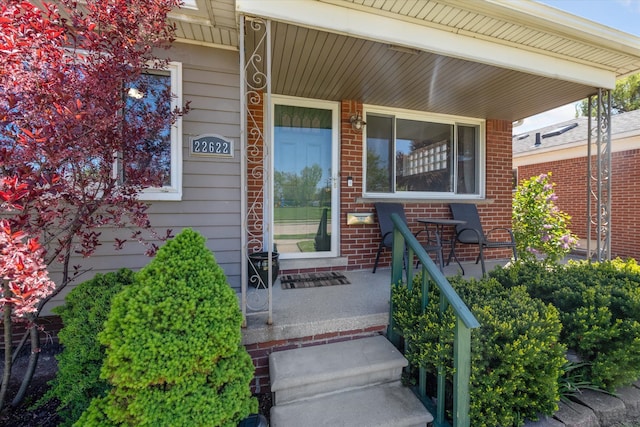 entrance to property with covered porch and brick siding