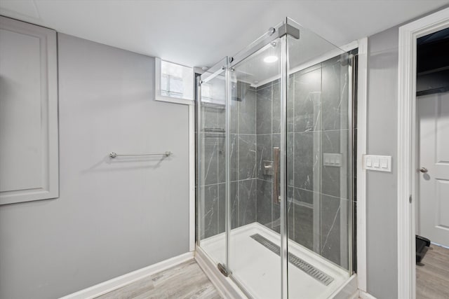 bathroom with wood finished floors, a stall shower, and baseboards