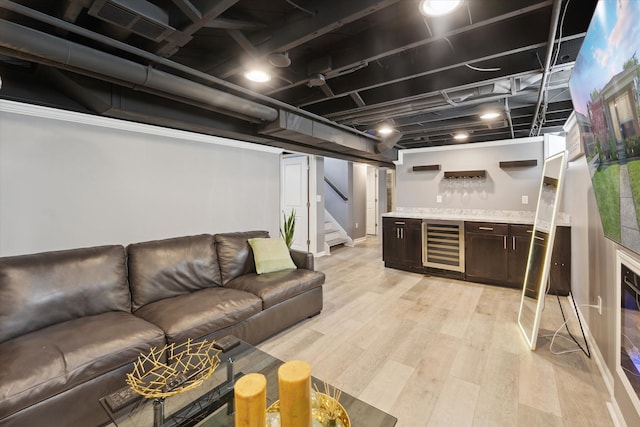 finished below grade area featuring a bar, beverage cooler, stairs, and light wood-type flooring