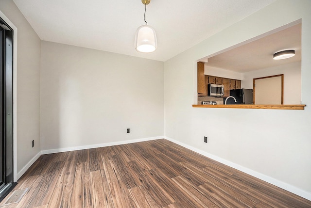 unfurnished dining area featuring baseboards, visible vents, and dark wood finished floors