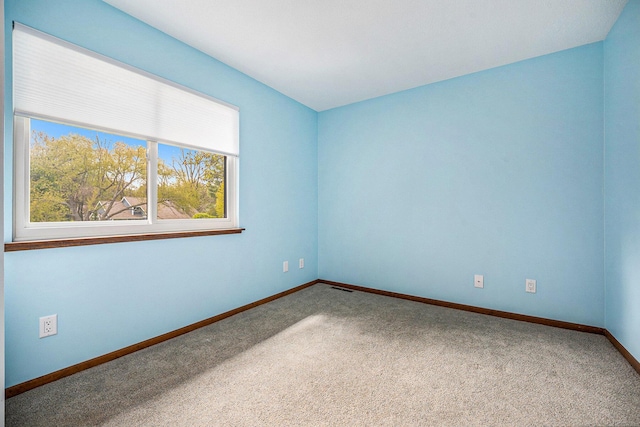 spare room featuring carpet floors, baseboards, a healthy amount of sunlight, and visible vents