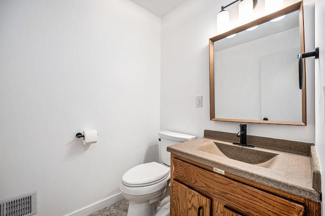 half bath featuring toilet, baseboards, vanity, and visible vents