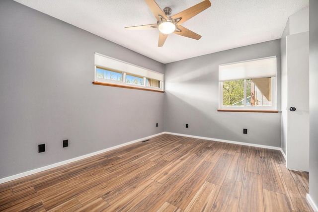 spare room with baseboards, ceiling fan, plenty of natural light, and wood finished floors