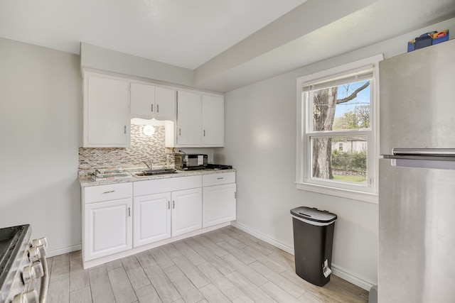 kitchen featuring stainless steel appliances, backsplash, baseboards, light wood-style floors, and light countertops
