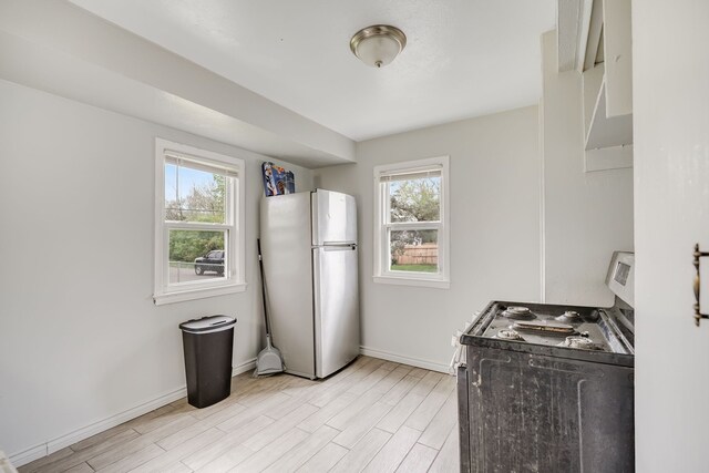 kitchen featuring stainless steel appliances, baseboards, and light wood-style flooring
