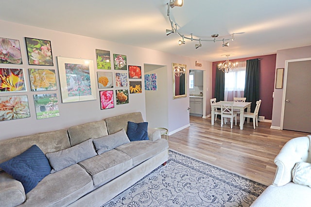 living area featuring a chandelier, light wood-style floors, and baseboards