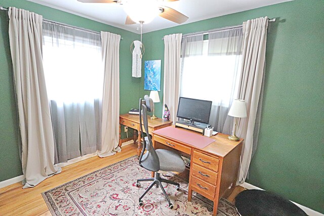 home office featuring plenty of natural light, a ceiling fan, wood finished floors, and baseboards