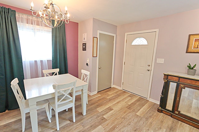 dining room with a chandelier, light wood-type flooring, and baseboards