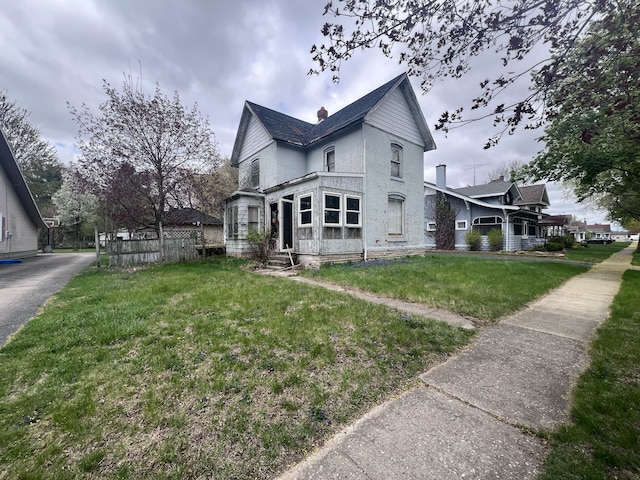 view of property exterior featuring brick siding, entry steps, a chimney, and a lawn