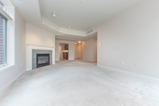 unfurnished living room featuring baseboards, a fireplace, visible vents, and light colored carpet